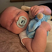 Michael is registered to the contest to win money with this photo: baby, sleeping, pacifier, stuffed_animal, hand, arm, skin, comfort, rest, infant, closeup, indoor, soft_toy, child, cute, peaceful, holding, relaxation, human, cozy