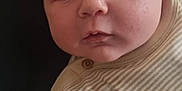 Michael is registered to the contest to win money with this photo: arm, baby, background, cheeks, closeup, clothing, cute, expression, eyes, face, indoor, infant, laying, onesie, person, portrait, skin, soft_light, striped, texture