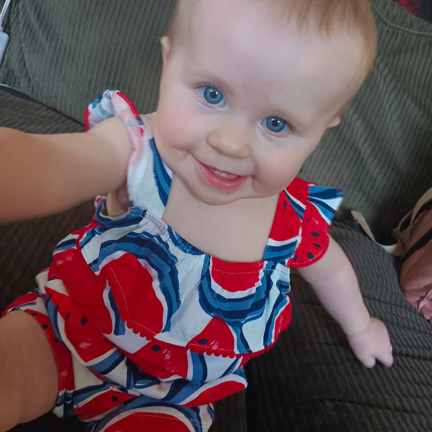 Rozalynia is registered to the contest to win money with this photo: arm, baby, blue_eyes, child, closeup, colorful_clothing, couch, cute, hand, happy, indoor, infant, one_person, person, portrait, short_hair, sitting, skin, smiling, watermelon_pattern