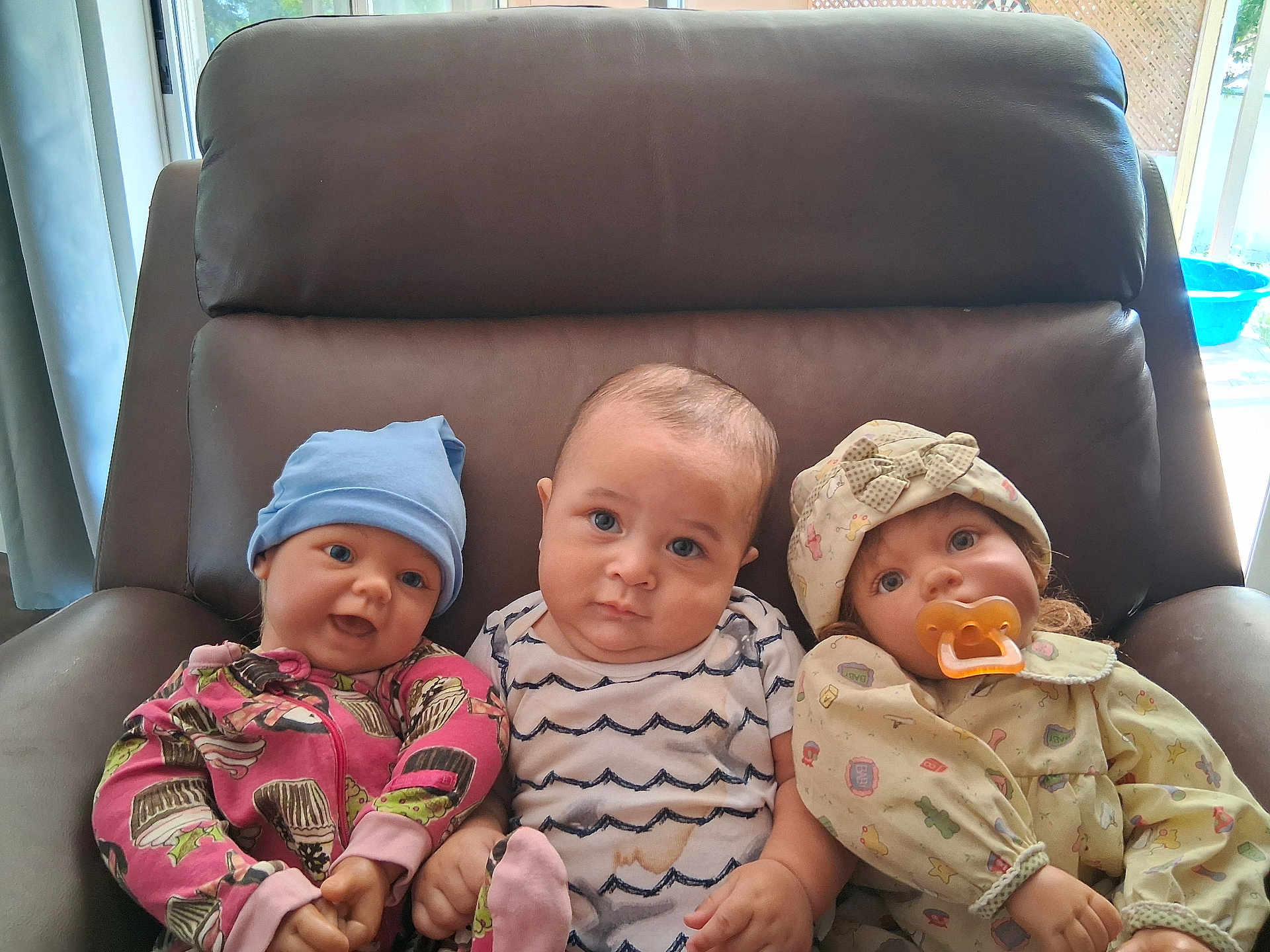 Jayce joined the competition — help win amazing prizes! baby, doll, chair, leather, hat, pacifier, clothing, child, indoor, portrait, expression, three, seated, realistic_doll, blue_eyes, pink, beige, patterned, cute, toy