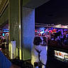 Prince joined the competition — help win amazing prizes! dog, bar, bottle, leash, person, indoor, crowd, lights, counter, beverage, nightlife, fluffy, seated, wall, paper_towel, refrigerator, people, colorful_lighting, table, hand