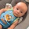 baby, infant, child, onesie, blue_clothing, cartoon, monkey, seat, cushion, indoor, portrait, face, cute, expression, looking_at_camera, skin, head, arms, baby_seat, clothing