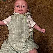 Julian is registered to the contest to win money with this photo: baby, infant, carpet, overalls, striped_clothing, white_shirt, lying_down, face, head, drool, child, cute, indoor, skin, small_arm, small_leg, button, fabric, floor, casual