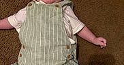 Julian is registered to the contest to win money with this photo: baby, button, carpet, casual, child, cute, drool, fabric, face, floor, head, indoor, infant, lying_down, overalls, skin, small_arm, small_leg, striped_clothing, white_shirt