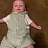 baby, infant, carpet, overalls, striped_clothing, white_shirt, lying_down, face, head, drool, child, cute, indoor, skin, small_arm, small_leg, button, fabric, floor, casual