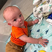 Julian joined the competition — help win amazing prizes! baby, child, infant, orange_shirt, brown_pants, playpen, blanket, dinosaur_pattern, toy, pacifier, curious, indoor, crawling, cute, young, person, face, hand, lying_down, colorful