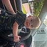 Julian joined the competition — help win amazing prizes! baby, child, car, steering_wheel, dashboard, paper_towel, window, person, seat, interior, clothing, hand, face, vehicle, instrument_panel, sunlight, road, trees, house, curious