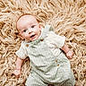baby, infant, smiling, overalls, white_shirt, fluffy_rug, beige, curious_expression, lying_down, indoors, child, cute, portrait, small_hands, bright_eyes, soft_texture, comfortable, casual_clothing, looking_up, young_child