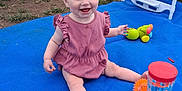 Leia is registered to the contest to win money with this photo: baby, child, outdoor, blue_blanket, pink_dress, toy, high_chair, grass, tent, car, smiling, sitting, playful, happy, daylight, barefoot, grass_patch, plastic_toy, camping, family