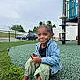 Sayora joined the competition — help win amazing prizes! child, smiling, playground, outdoor, grass, fence, car, denim_jacket, sandals, green_bows, black_shirt, curly_hair, play_structure, happy, sitting, person, park, daylight, casual_clothing, young_girl