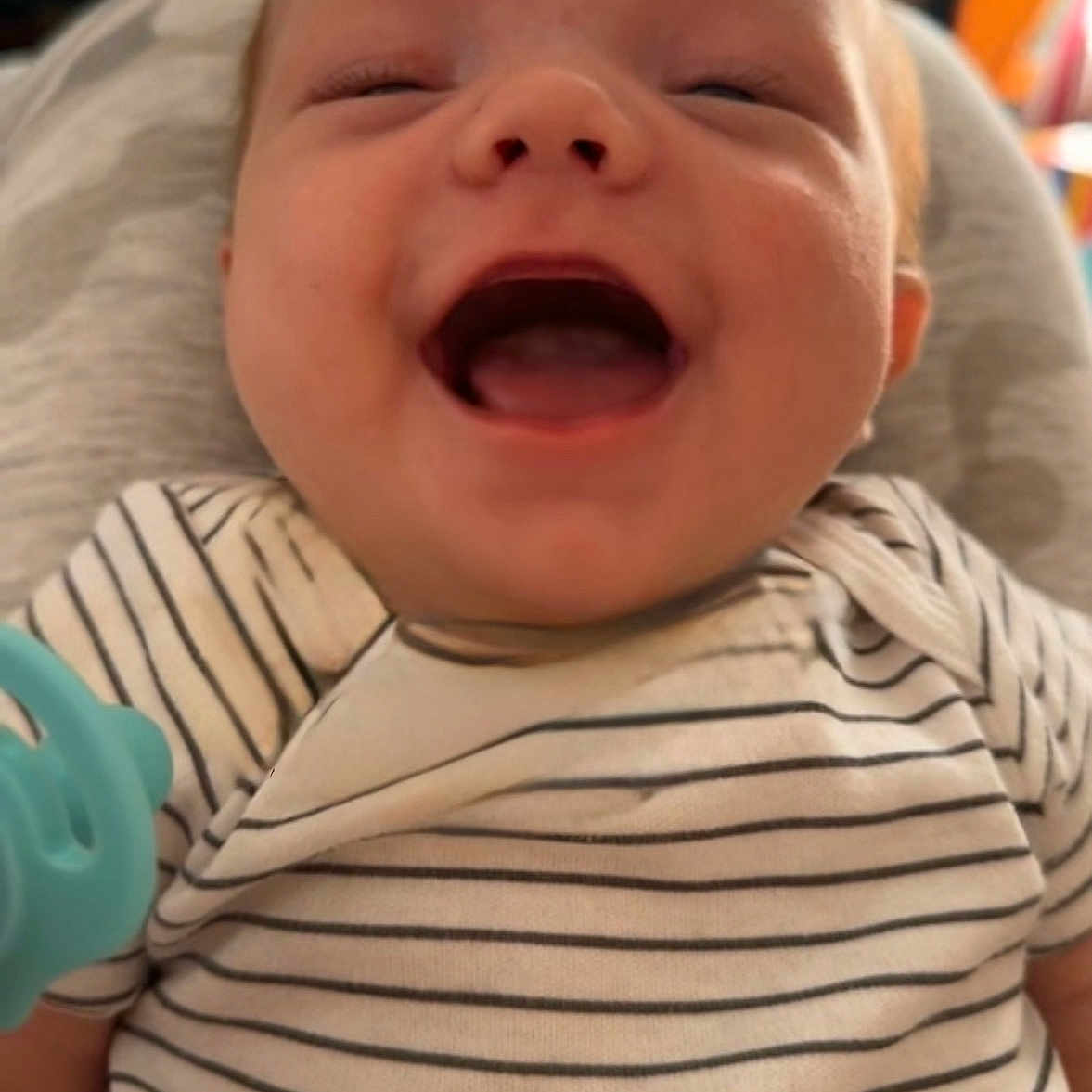 Liam is registered to the contest to win money with this photo: baby, blurred_background, child, closeup, cute, expression, face, happy, head, human, indoor, infant, joy, mouth_open, newborn, onesie, person, skin, smiling, striped_clothing