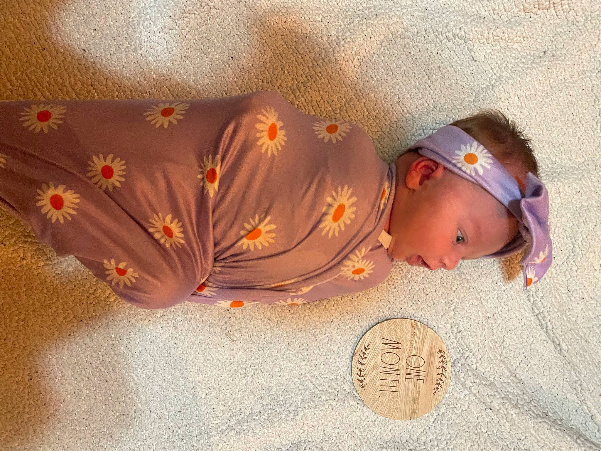 Ellie is registered to the contest to win money with this photo: baby, baby_toddler_clothing, child, costume_hat, fashion_accessory, flooring, flower, hair_accessory, headgear, headpiece, insect, jewellery, linens, orange, pattern, peach, person, petal, textile, toddler