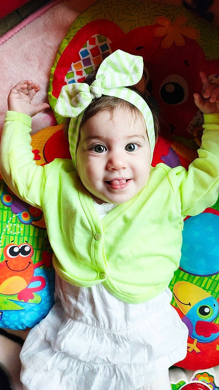 Lola a rejoint le concours — aidez-le/la à gagner de superbes lots ! baby, baby_toddler_clothing, cheek, child, face, facial_expression, fun, green, happy, headgear, iris, person, pink, product, skin, sleeve, smile, textile, toddler, white