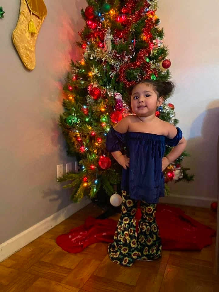 Angela is registered to the contest to win money with this photo: abdomen, christmas, christmas_decoration, christmas_eve, christmas_ornament, christmas_tree, costume_accessory, event, floor, flooring, holiday, holiday_ornament, interior_design, laminate_flooring, ornament, person, red, tradition, waist, wood_flooring