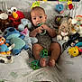 Lucas is registered to the contest to win money with this photo: baby, plush_toy, stuffed_animal, blanket, toy, infant, indoor, cute, child, couch, comfort, play, soft, smiling, face, person, blue, yellow, red, green