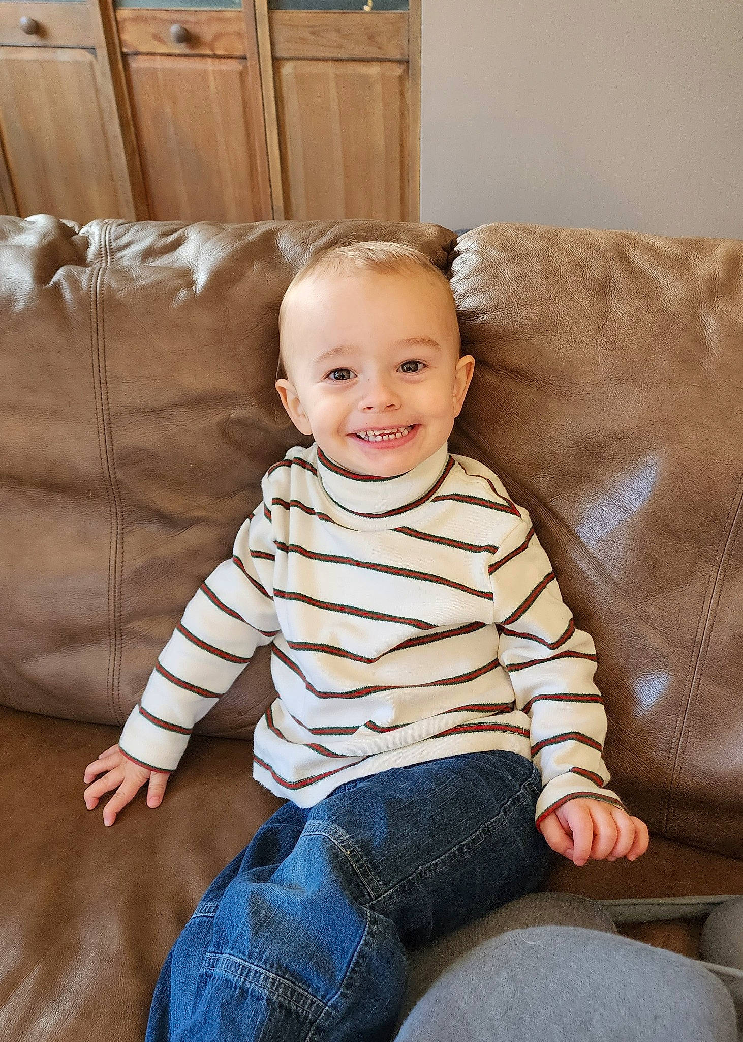 Conrad is registered to the contest to win money with this photo: baby_toddler_clothing, cheek, child, comfort, couch, eye, flash_photography, flooring, fun, happy, hardwood, head, jeans, joy, knee, person, sitting, skin, sleeve, smile