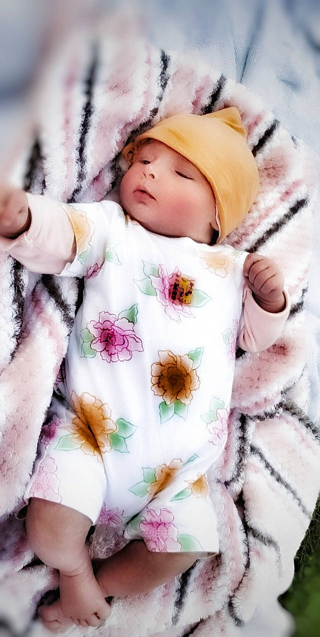 Niyanna a rejoint le concours — aidez-le/la à gagner de superbes lots ! baby, baby_sleeping, baby_toddler_clothing, beauty, cap, comfort, eye, face, fur_clothing, head, headgear, headwear, jacket, linens, person, pink, plant, skin, sleeve, textile