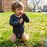 Jasmin is registered to the contest to win money with this photo: toddler, child, grass, outdoor, sunny, kneeling, onesie, brick_building, trees, smiling, playful, daylight, greenery, person, nature, casual, happy, baby, young_child, candid