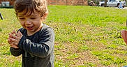 Jasmin is registered to the contest to win money with this photo: brick_house, casual_clothing, child, clapping, daylight, grass, greenery, happy, kneeling, nature, outdoor, person, playing, recreation, smiling, soccer_ball, sport, sunny, toddler, young_child