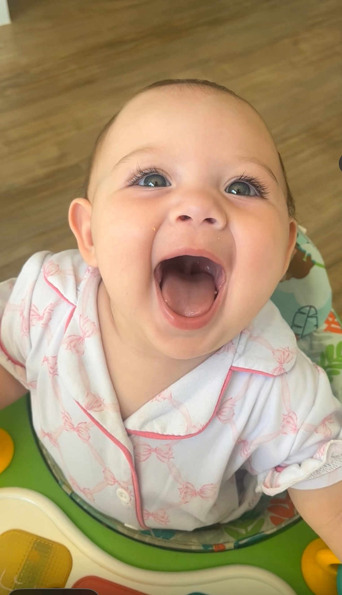 Aurora joined the competition — help win amazing prizes! baby, child, smiling, happy, face, mouth_open, eyes, clothing, pink, white, sitting, activity_center, toy, indoor, floor, wooden_floor, infant, cute, playful, portrait
