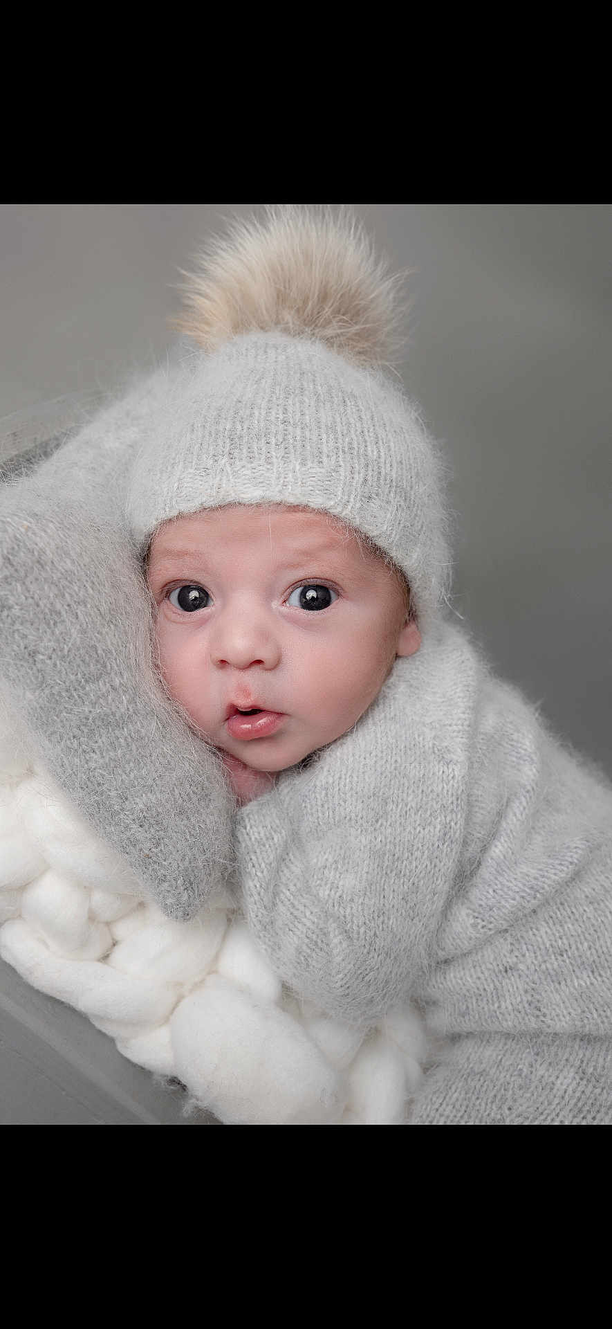 Kheylann a rejoint le concours — aidez-le/la à gagner de superbes lots ! baby, infant, newborn, beanie, pom_pom, knit_hat, sweater, blanket, soft_texture, cozy, gray, studio_portrait, big_eyes, surprised_expression, cute, cheeks, close_up, portrait, wool, cuddling