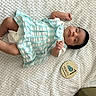 baby, infant, child, dress, striped_clothing, white_blanket, milestone_marker, one_month, lying_down, peaceful, cute, small_hand, small_feet, soft_texture, indoors, portrait, newborn, resting, cozy, sleepy