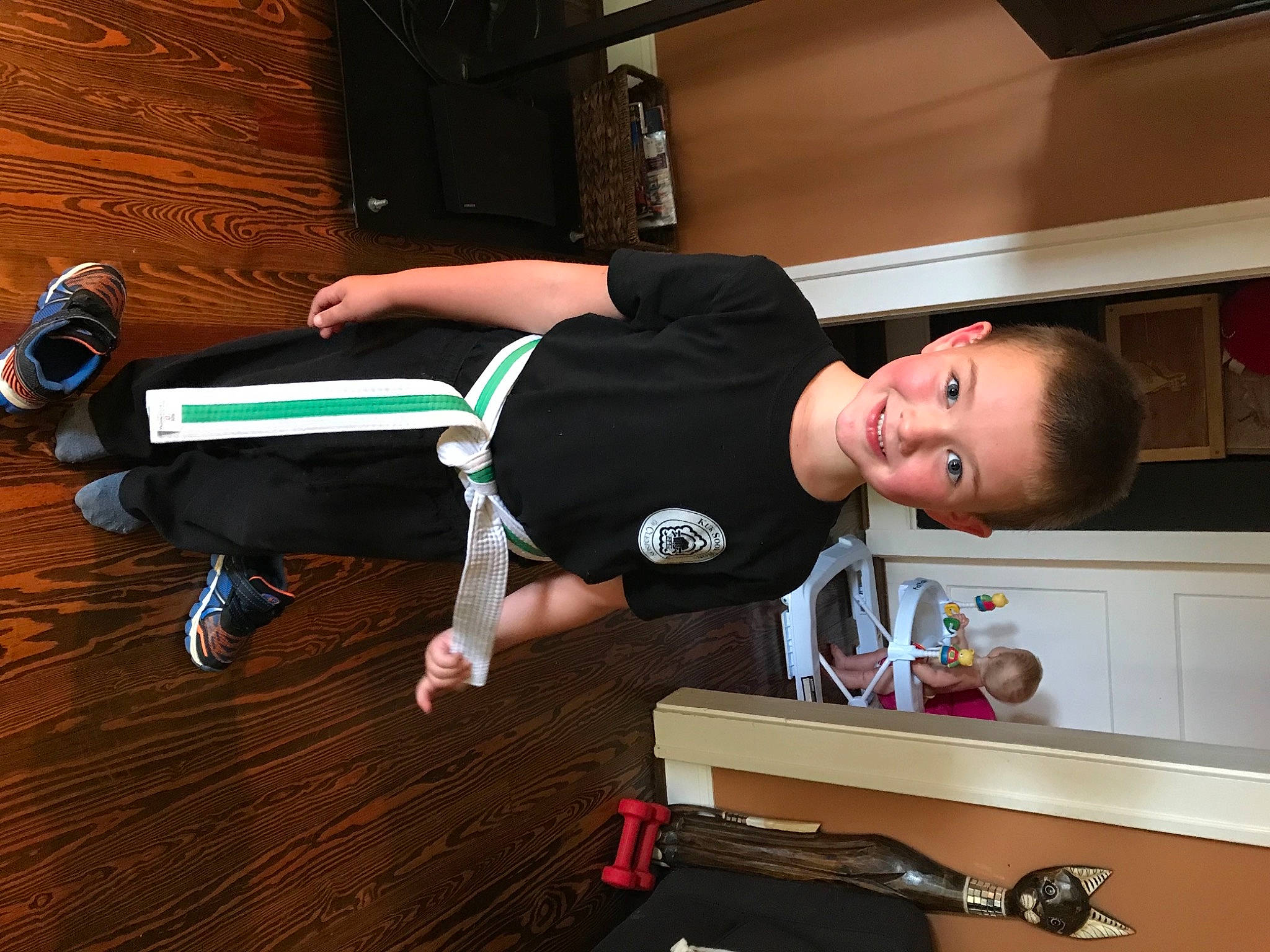 Coleman is registered to the contest to win money with this photo: cabinetry, child, comfort, elbow, flooring, fun, hardwood, human_leg, joy, knee, musical_instrument_accessory, person, recreation, refrigerator, room, sitting, smile, thigh, toddler, varnish