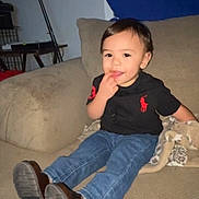 Joaquin is registered to the contest to win money with this photo: toddler, child, couch, blanket, jeans, shirt, indoor, furniture, footwear, smiling, person, seated, casual_clothing, home, cute, young_child, happy, portrait, cozy, relaxed