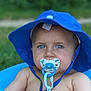 baby, blue_hat, pacifier, blue_eyes, close_up, outdoor, summer, child, skin, face, infant, cute, portrait, sun_hat, green_background, baby_toy, baby_boy, soft_focus, daylight, chained_pacifier