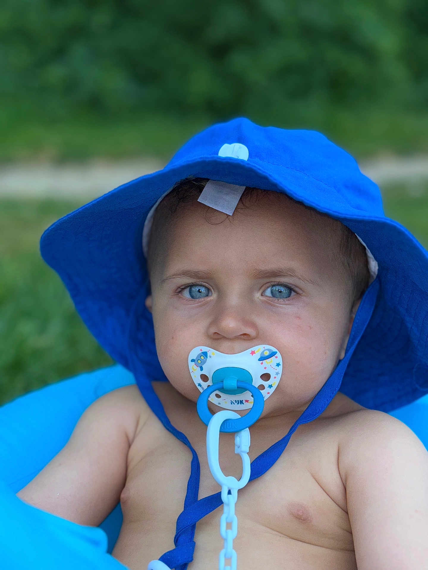 Seydou a rejoint le concours — aidez-le/la à gagner de superbes lots ! baby, blue_hat, pacifier, blue_eyes, close_up, outdoor, summer, child, skin, face, infant, cute, portrait, sun_hat, green_background, baby_toy, baby_boy, soft_focus, daylight, chained_pacifier