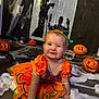 baby, carved_pumpkins, celebration, child, costume, crawling, cute, decorations, festive, fun, green_bow, halloween, holiday, indoor, orange, party, pumpkin_costume, shadow_puppets, smiling, spider_web