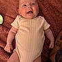 baby, infant, smiling, onesie, blanket, lying_down, happy, child, human, skin, arm, tattoo, cute, face, person, indoors, soft, comfortable, newborn, pink