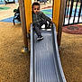 Kaïs participe au concours pour gagner de l'argent avec cette photo : child, toddler, slide, playground, play_equipment, jacket, sneakers, outdoor, recreation, fun, young_child, curious, yellow, gray_slide, rubber_flooring, park, daytime, activity, casual_clothing, person
