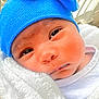 baby, newborn, blue_hat, blanket, close_up, infant, sleepy, outdoor, porch, white_clothing, face, cute, wrapped, soft_texture, child, headwear, warm, peaceful, person, skin