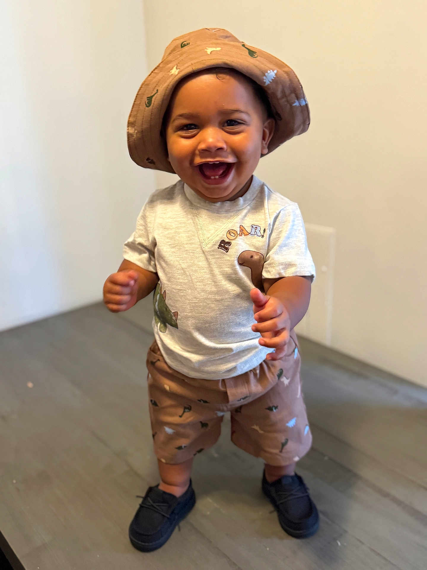 Zamari is registered to the contest to win money with this photo: toddler, child, smile, happy, standing, hat, shorts, tshirt, shoes, floor, indoor, person, dinosaur, clothing, cute, baby, young_child, joyful, playful, portrait