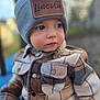 toddler, child, hat, beanie, jacket, plaid, face, portrait, outdoor, cold_weather, young_child, curious, warm_clothing, button, eyewear, closeup, person, cute, soft_focus, winter