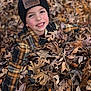 child, boy, leaves, autumn, outdoor, smiling, hat, plaid_jacket, face, nature, play, fall, happy, seasonal, park, casual_clothing, person, fun, leaf_pile, cheerful