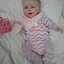 Octavia joined the competition — help win amazing prizes! baby, infant, bed, blanket, pink, purple, onesie, bib, toy, sleepy, lying_down, child, smiling, indoor, soft, cute, person, young_child, plush, cozy
