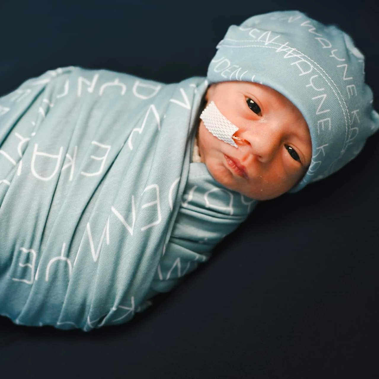 Kayden is registered to the contest to win money with this photo: baby, blanket, blue, child, cute, dark_background, face, hat, hospital, infant, lying_down, medical_tape, newborn, peaceful, portrait, resting, small, soft, swaddled, wrapped