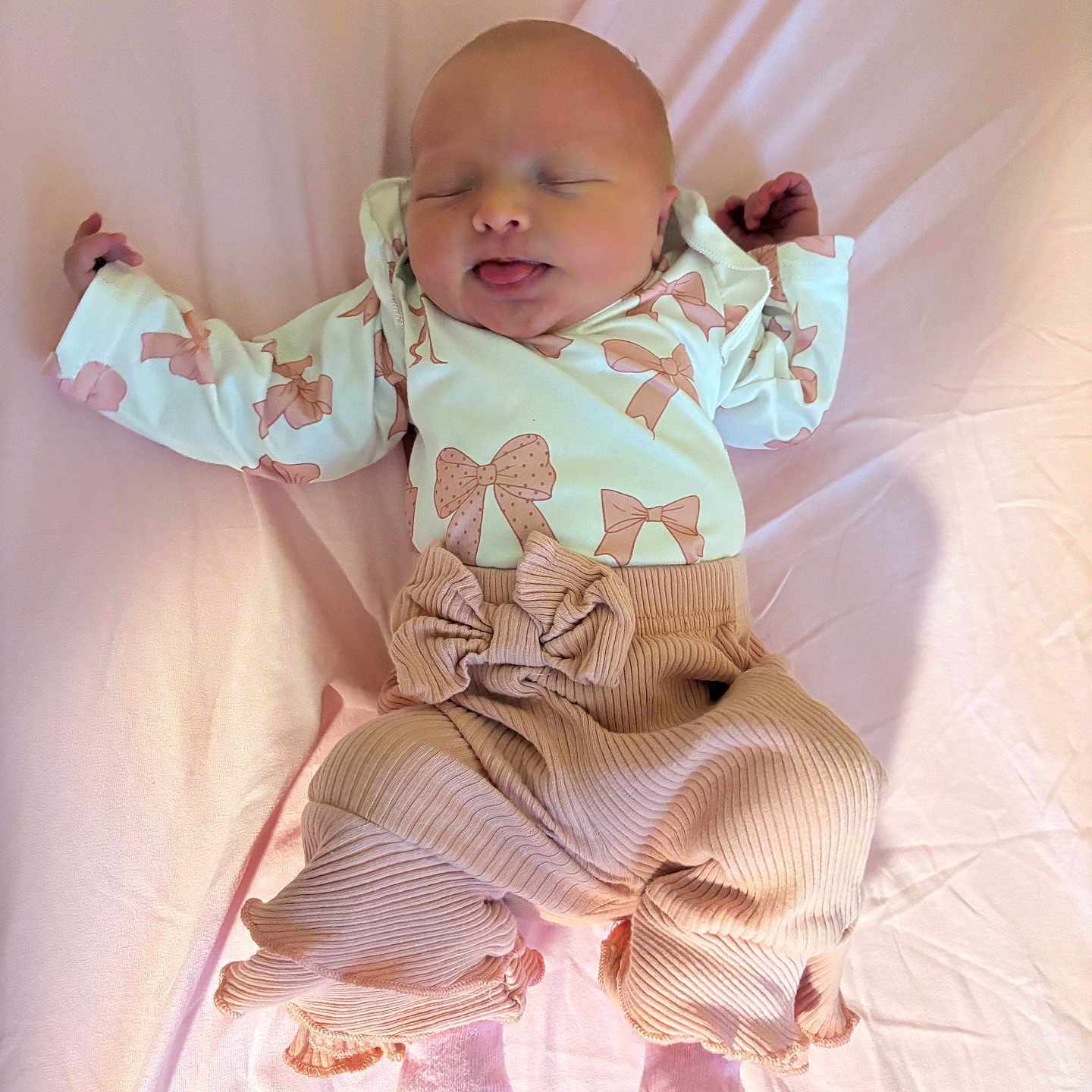 Autumn is registered to the contest to win money with this photo: baby, newborn, infant, sleeping, tongue_out, pink_blanket, clothing, bows, pastel_colors, cute, soft_texture, cozy, child, portrait, lying_down, small_hands, small_feet, indoors, peaceful, adorable