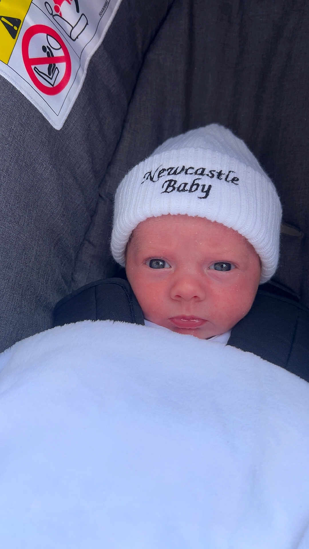 Alfie joined the competition — help win amazing prizes! baby, newborn, hat, white_blanket, car_seat, face, infant, child, cozy, cute, portrait, closeup, expression, warning_label, clothing, baby_hat, newcastle_baby, wrapped, indoor, seat