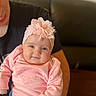 baby, infant, child, pink_sweater, headband, flower, adult, arm, sofa, indoor, portrait, smile, cute, cozy, person, clothing, heart_pattern, casual, skin, face