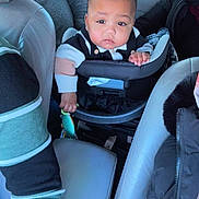 Yamin is registered to the contest to win money with this photo: adult, baby, car_interior, car_seat, child, clothing, face, hand, head, jacket, leather_seat, person, road, seat, seatbelt, toy, travel, vehicle, window, winter_wear