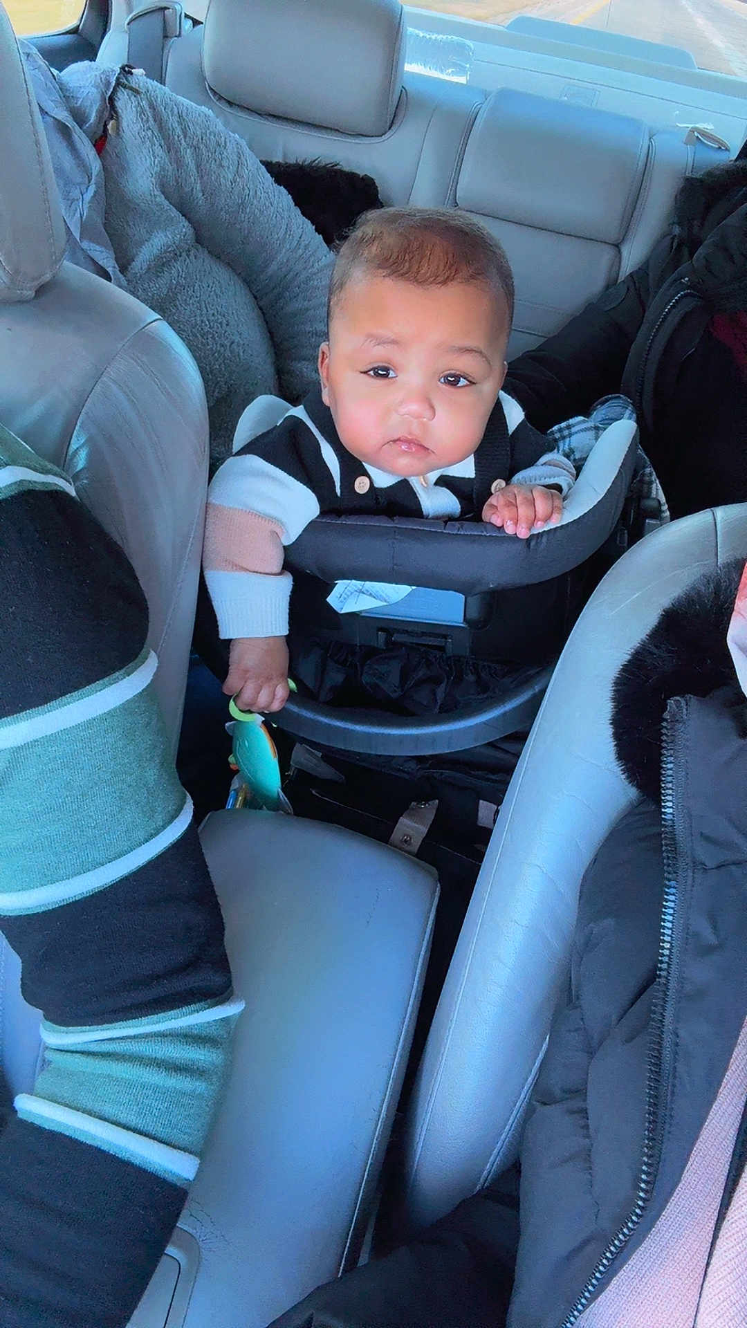 Yamin is registered to the contest to win money with this photo: adult, baby, car_interior, car_seat, child, clothing, face, hand, head, jacket, leather_seat, person, road, seat, seatbelt, toy, travel, vehicle, window, winter_wear