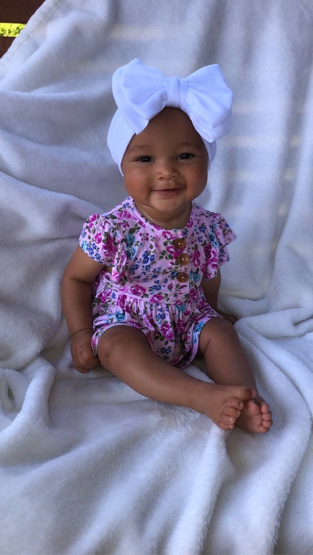 Diamond is registered to the contest to win money with this photo: baby, baby_toddler_clothing, child, chin, comfort, dress, face, facial_expression, happy, head, headwear, joy, magenta, person, pink, product, purple, skin, sleeve, smile