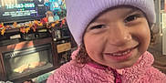 Arianelys Otero joined the competition — help win amazing prizes! child, smile, pink_jacket, beanie, indoor, living_room, television, autumn_decor, furniture, cozy, curly_hair, face, person, warm_clothing, casual, home, entertainment, colorful, happy, portrait