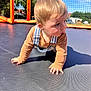 toddler, child, crawling, trampoline, outdoor, net, orange, blue_sky, sunlight, tree, grass, clothing, overalls, long_sleeve, face, hands, shadow, daytime, play, curious