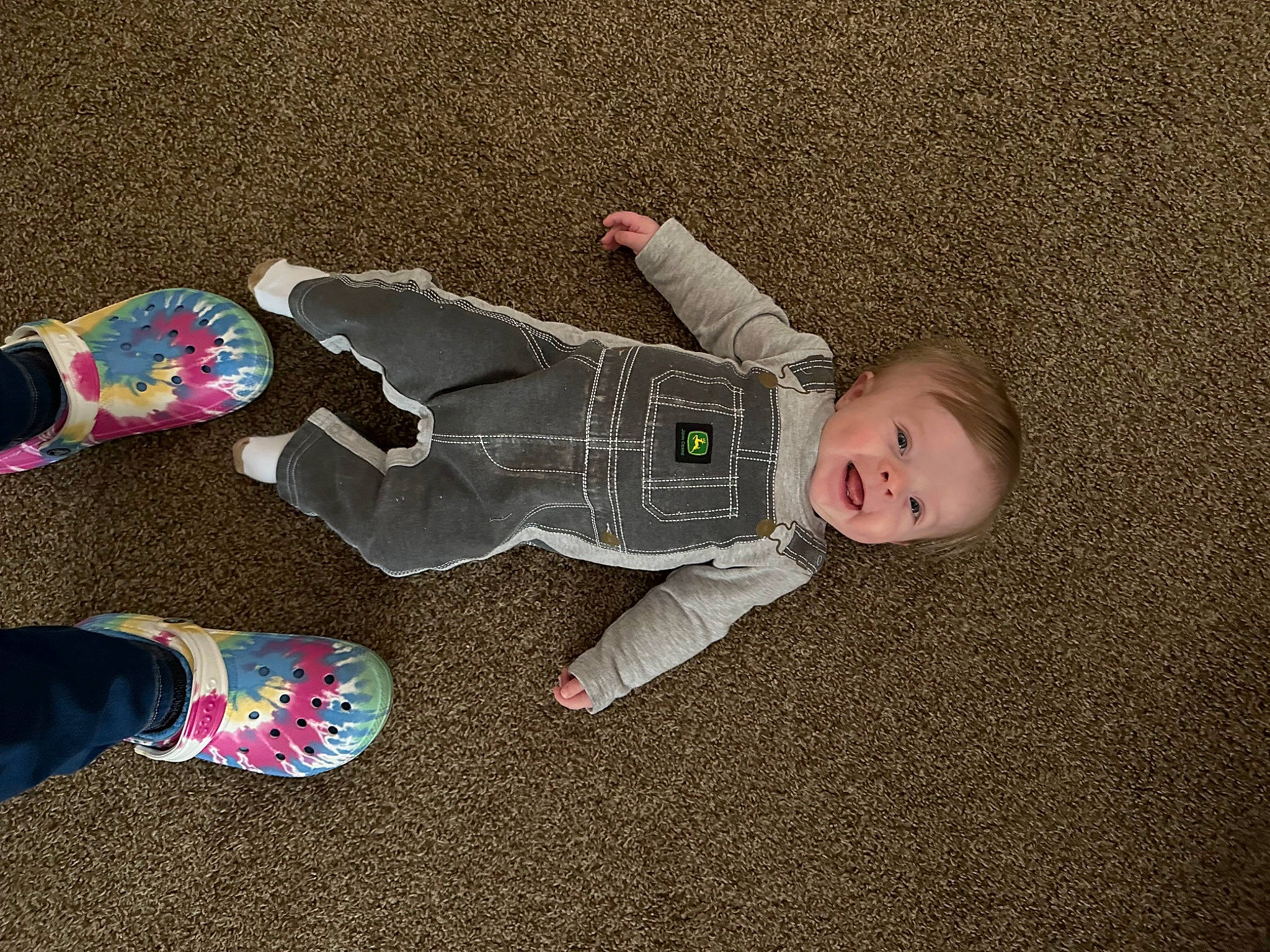 Dylan is registered to the contest to win money with this photo: baby, baby_toddler_clothing, carmine, child, comfort, floor, flooring, foot, fun, grass, head, human_leg, pattern, person, sitting, sleeve, smile, sock, toddler, walking_shoe