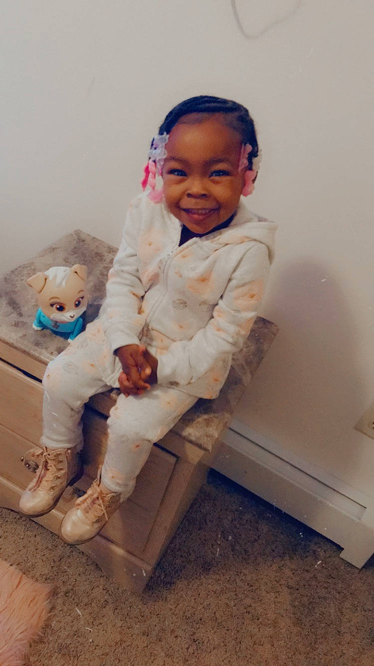 Kaniyah is registered to the contest to win money with this photo: baby, baby_toddler_clothing, child, comfort, face, flash_photography, flooring, formal_wear, fur, happy, head, human_leg, joy, knee, leg, person, sitting, sleeve, smile, t_shirt