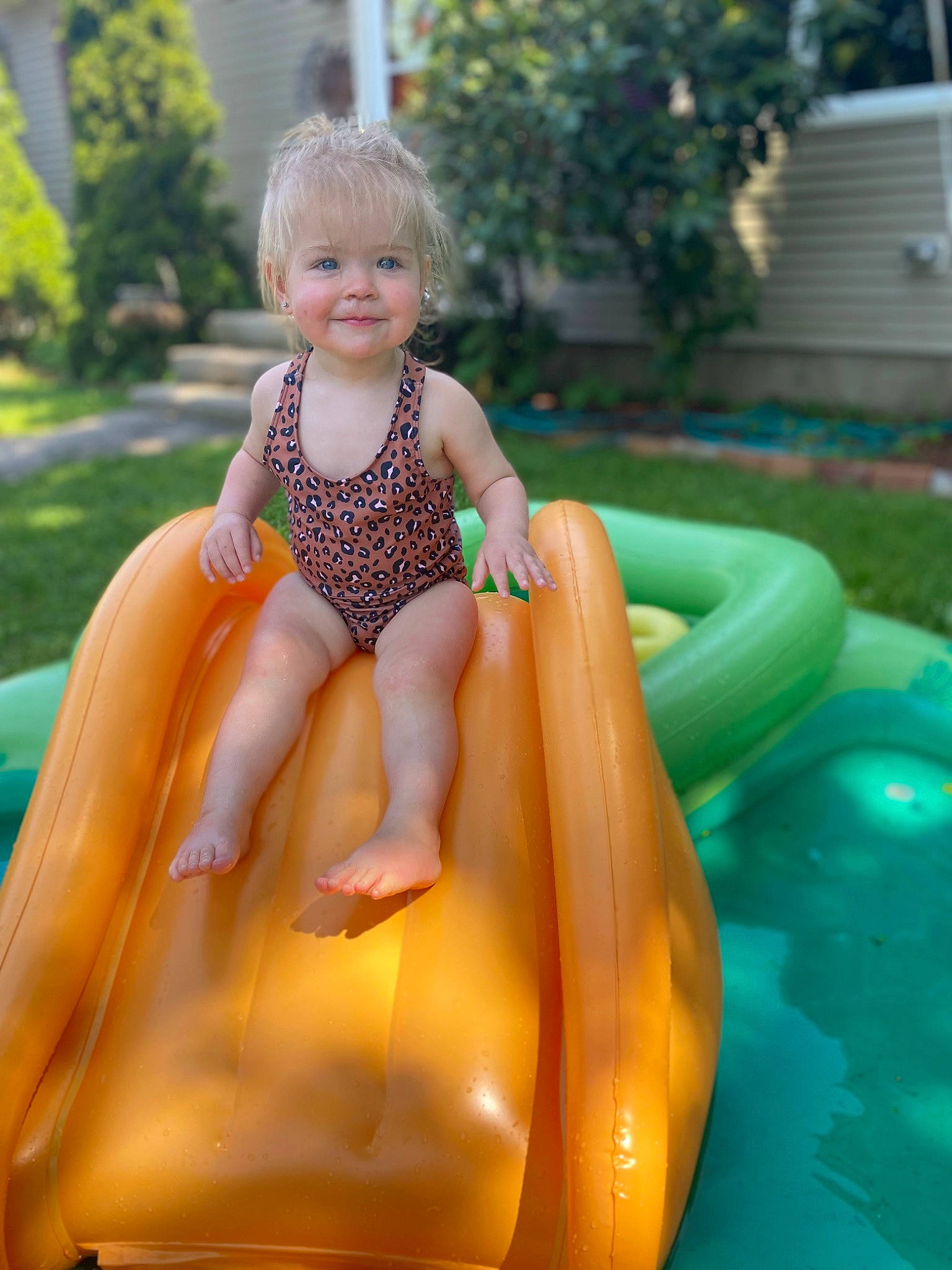 Charlotte is registered to the contest to win money with this photo: baby_toddler_clothing, child, chute, city, face, fun, grass, head, joy, leg, leisure, outdoor_play_equipment, person, plant, play, playground, recreation, sitting, smile, swimwear